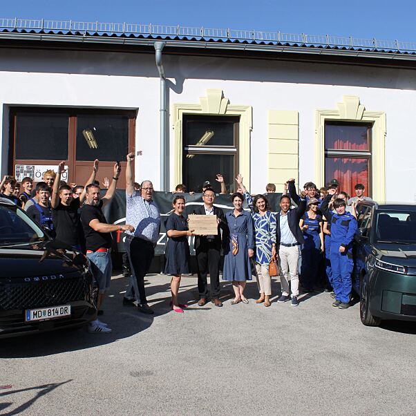 Vertreter: innen von Colmobil und der HTL Mödling mit Schüler: innen und den beiden neuen Ausbildungsfahrzeugen OMODA 5 HEV und JAECOO 5 BEV.