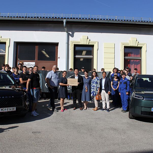Vertreter: innen von Colmobil und der HTL Mödling mit Schüler: innen und den beiden neuen Ausbildungsfahrzeugen OMODA 5 HEV und JAECOO 5 BEV.