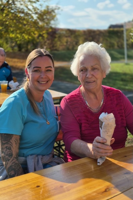 Mitarbeiterin Manuela Mocnik und Bewohnerin Ludmilla Rathmanner genießen beim gemütlichen Maronibraten das herrliche Bilderbuchwetter und die fröhliche Herbststimmung.