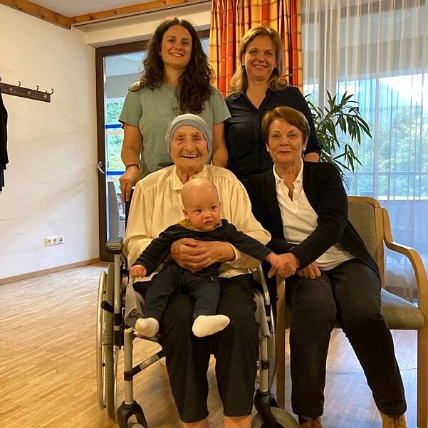 Fünf Generationen einer Familie lächeln strahlend für die Kamera