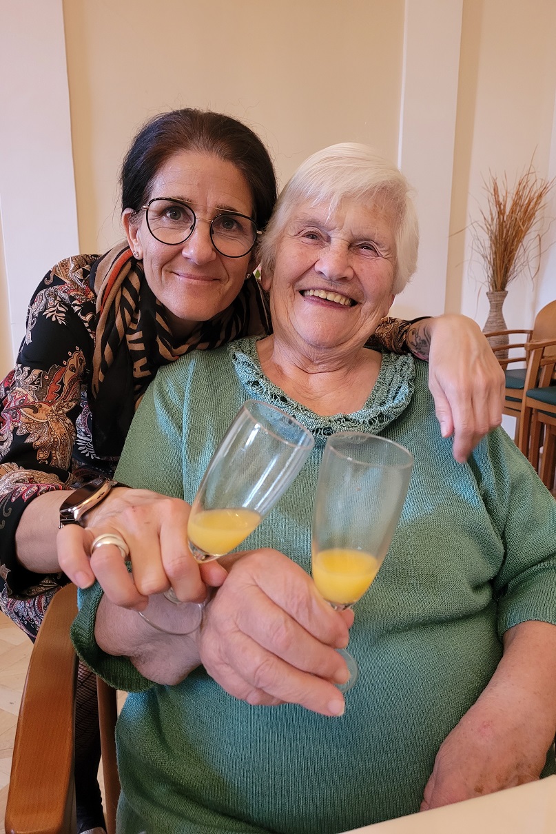 Bewohnerin Anna Fasching und Mitarbeiterin Barbara Großmann stoßen gemeinsam an. 